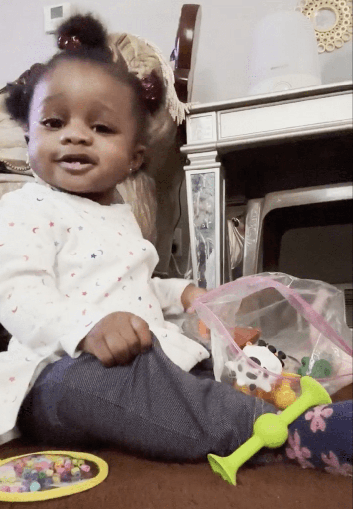 A cheerful young child from a Nigerian-American family plays with colorful toys during a Help Me Grow home visit.